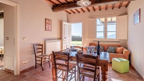 A dining area with a wooden table, chairs, and a view of the outdoors. - Il Girasole Apartment with Swimming Pool (Capannori)