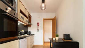 Une cuisine compacte équipée d’un lave-vaisselle, d’une cuisinière et d’un petit coin repas avec une table et des chaises.