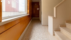 Un couloir avec une fenêtre, des murs en bois, un sol carrelé et un escalier.
