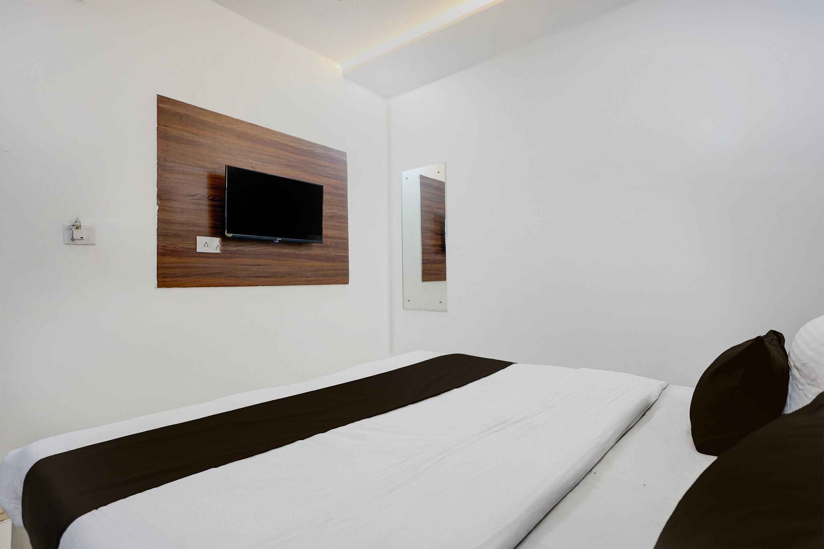 Een hotelkamer met een bed, een wandtelevisie en een spiegel.