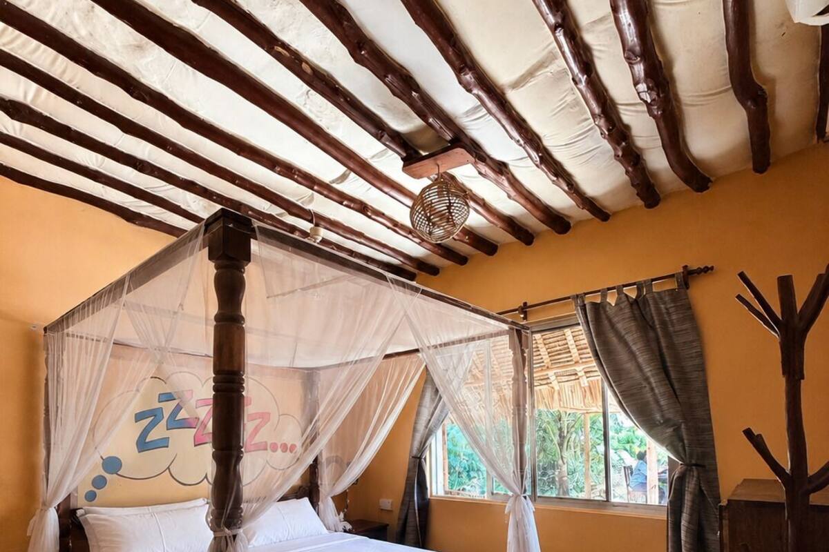 A room with a four-poster bed, a woven basket, and a window with curtains.