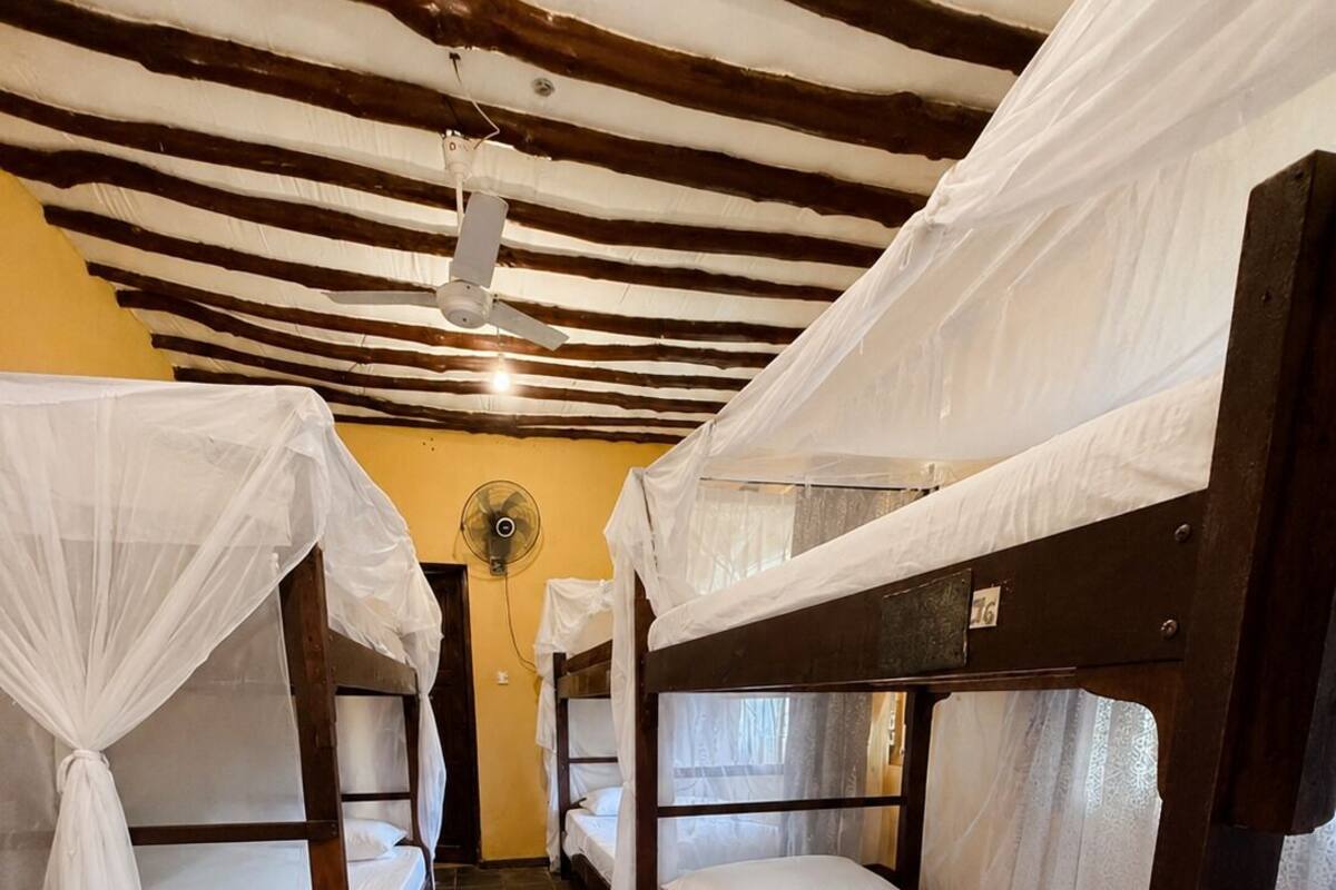 A room with four bunk beds, a ceiling fan, and a tiled floor.