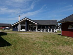A modern building with a sloped roof, large windows, and a fenced porch. - 4 Star Holiday Home in Grossenbrode (Grossenbrode)