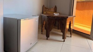 Ein kleines Zimmer mit einem Tisch, einem Stuhl und einem Kühlschrank.