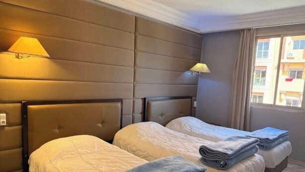 Ein Hotelzimmer mit zwei Betten, einem Kopfteil, einer Lampe und einem Fenster mit Blick.