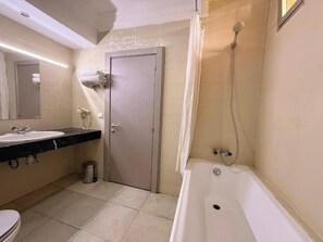 Een bad/douchecombinatie, handdoeken, zeep, toiletpapier