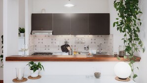 Une cuisine moderne avec des meubles de couleur sombre, un pare-feu en carreaux et un plan de travail en bois.