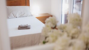 Un lit bien fait, avec une serviette pliée, une tête de lit en bois et une table de chevet sur laquelle se trouve une lampe.