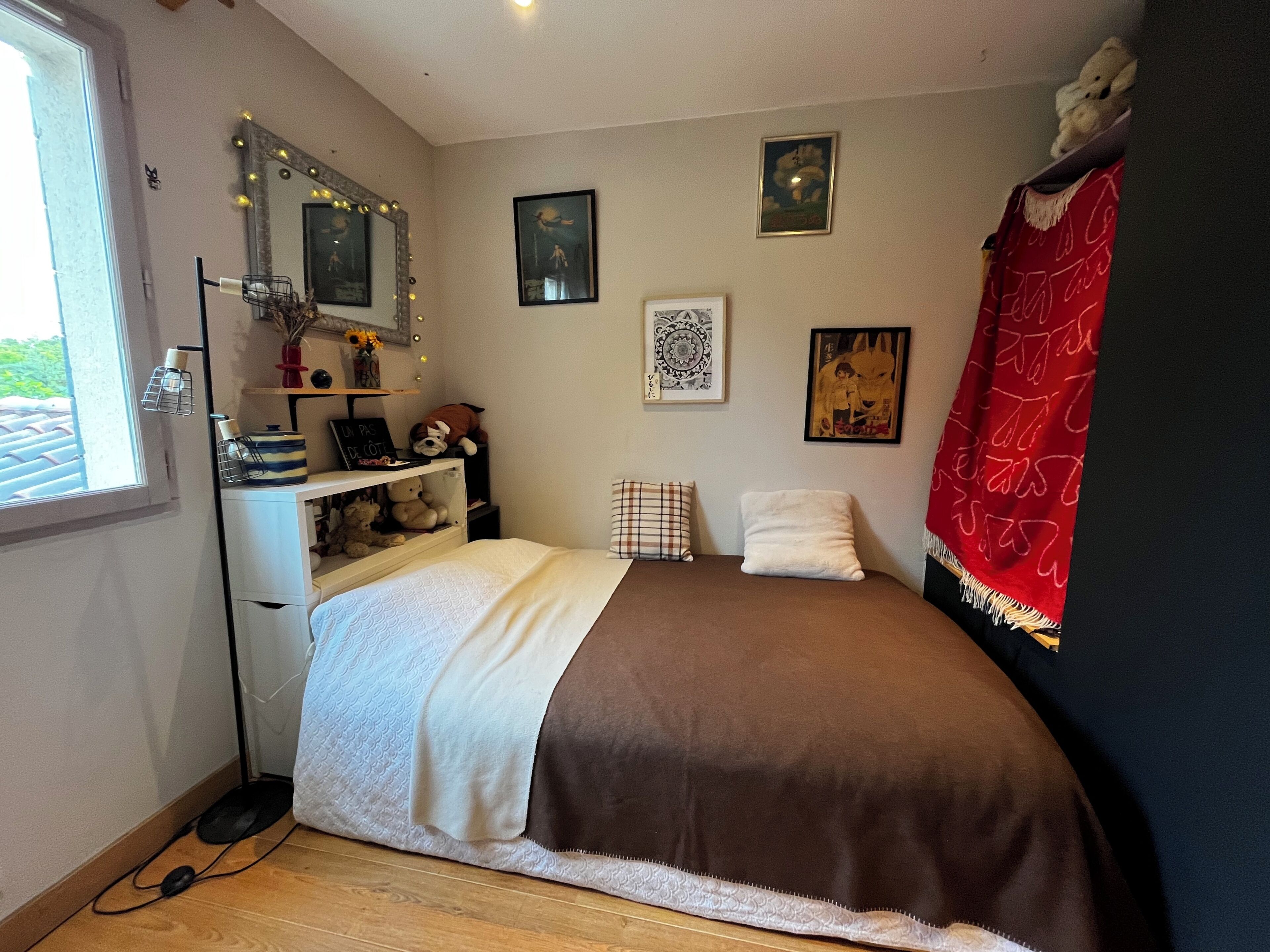 Quarto com cama, cómoda, espelho iluminado e quadros nas paredes.