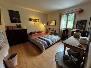 Une chambre à coucher comprenant un lit, une commode, des tables de chevet, une bibliothèque et une fenêtre.