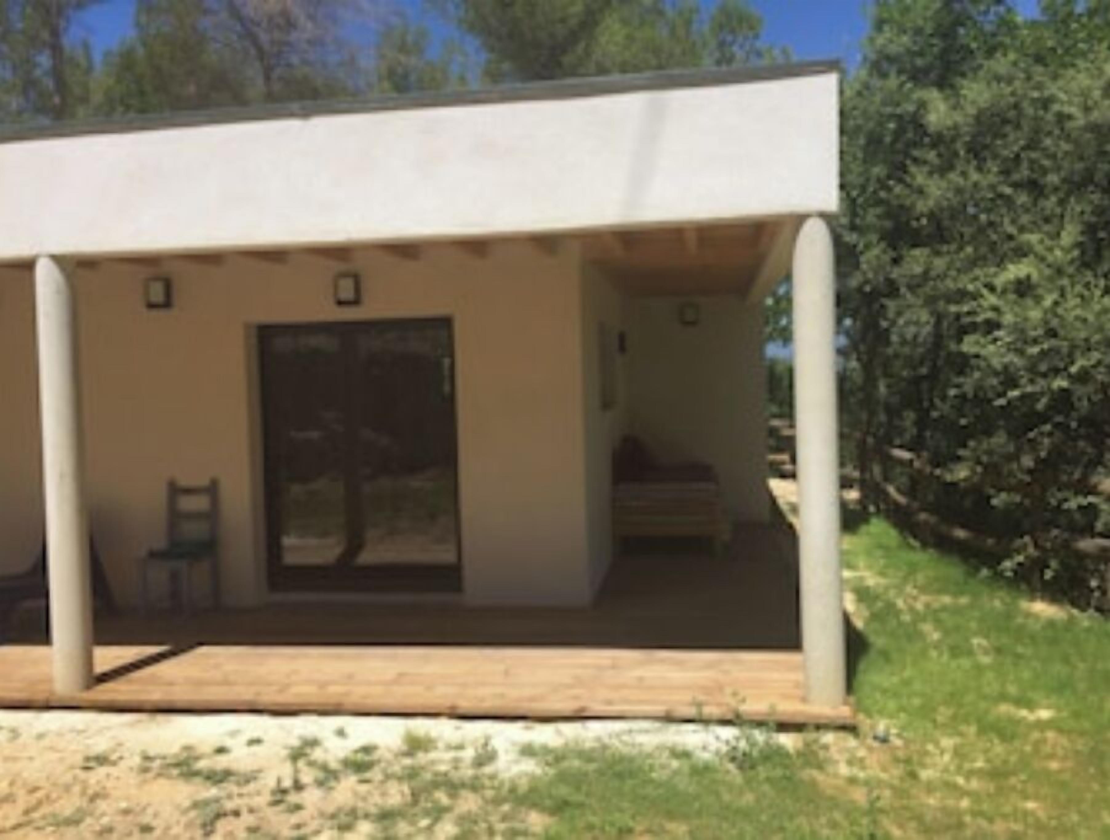 Un bâtiment moderne, de plain-pied, doté d’un porche abrité, d’une porte et d’un petit espace salon.