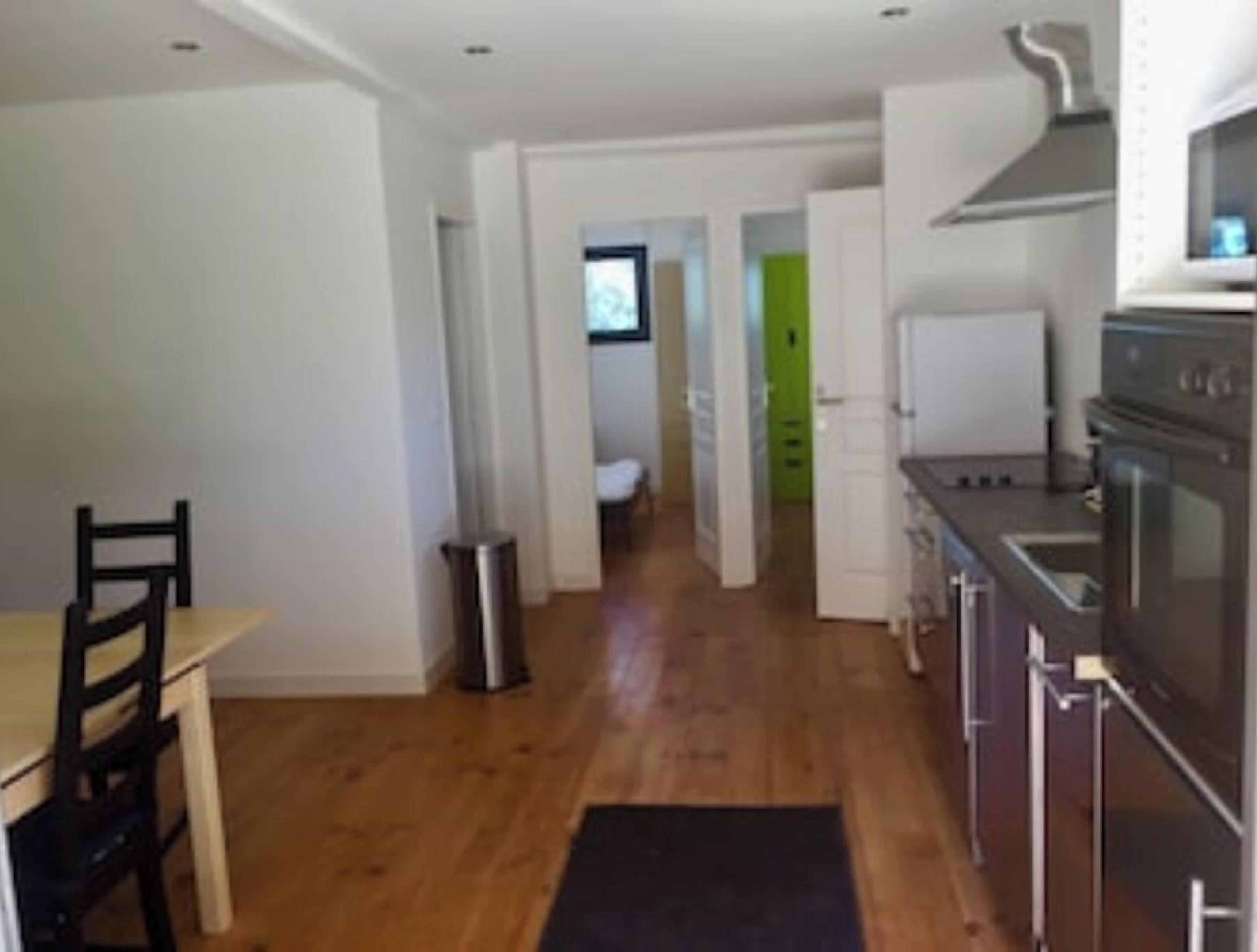 Cozinha pequena com área de refeições, lixeira e vista para outro cômodo.