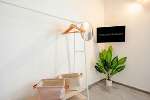 Una habitación minimalista con pared blanca, un letrero negro, una planta en maceta y cajas de almacenamiento.
