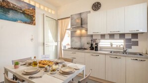 A modern kitchen with a dining table set for a meal, a gas stove, and a clock on the wall.