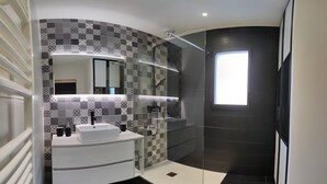 Une salle de bain moderne avec un meuble-lavabo blanc, une douche en verre et des carreaux décoratifs.