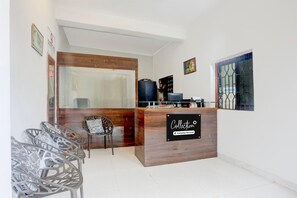 A reception desk with a sign reading 'Collection,' a wooden counter, a chair, and a glass door.