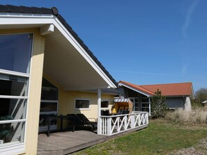 Een geel gebouw met een overdekte veranda, een tafel en stoelen.
