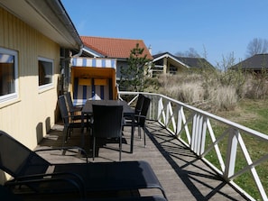 Eine Terrasse mit Gartenmöbeln, einem überdachten Sitzbereich und einem weißen Geländer.