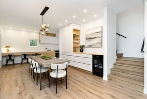 Eine moderne Küche mit Essbereich, Holzboden und einer Treppe.