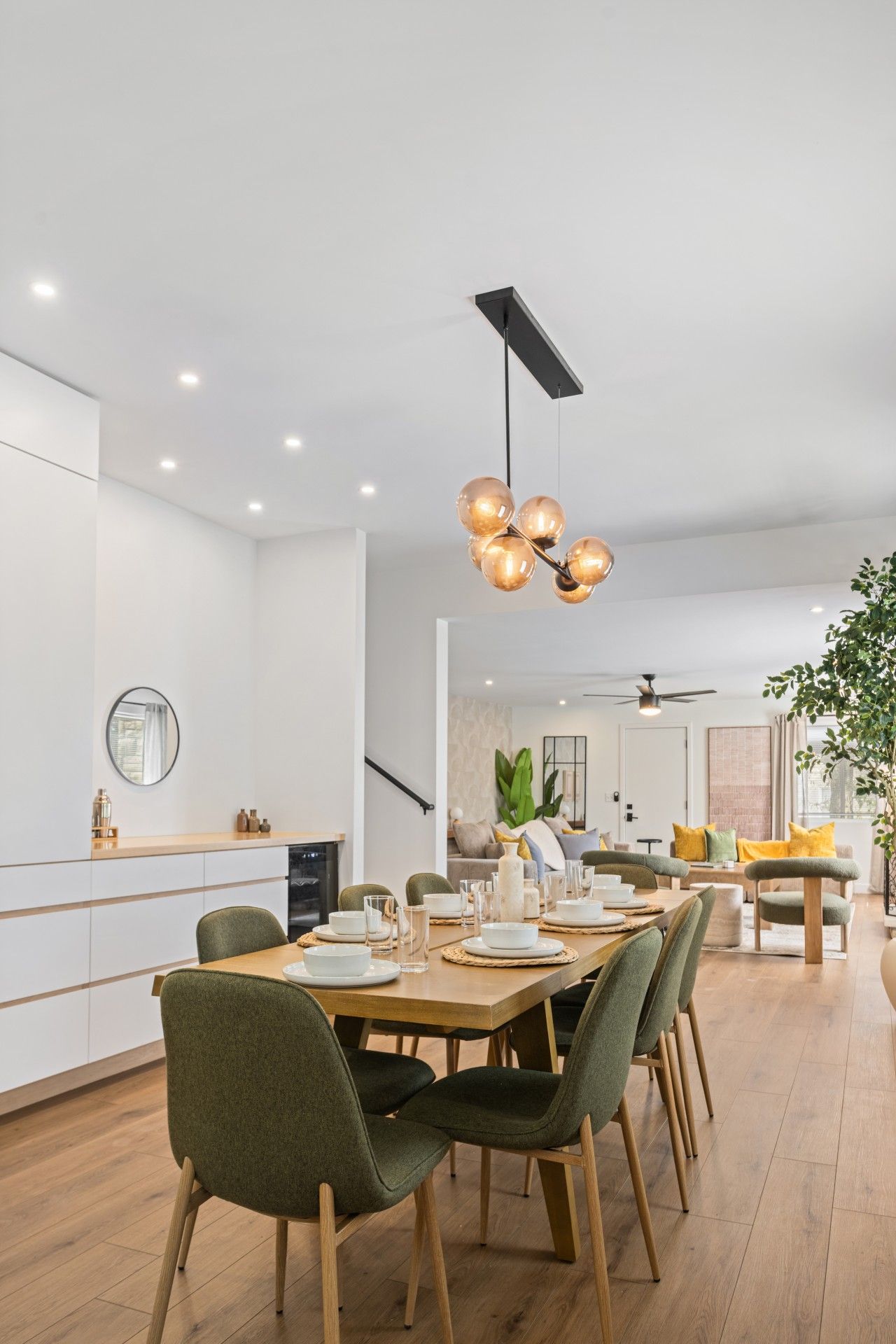 Una cocina moderna con comedor, que incluye una isla central, iluminación colgante y vista al salón.