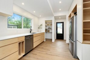 Eine moderne Küche mit Holzschränken, einem Geschirrspüler und einem Kühlschrank.