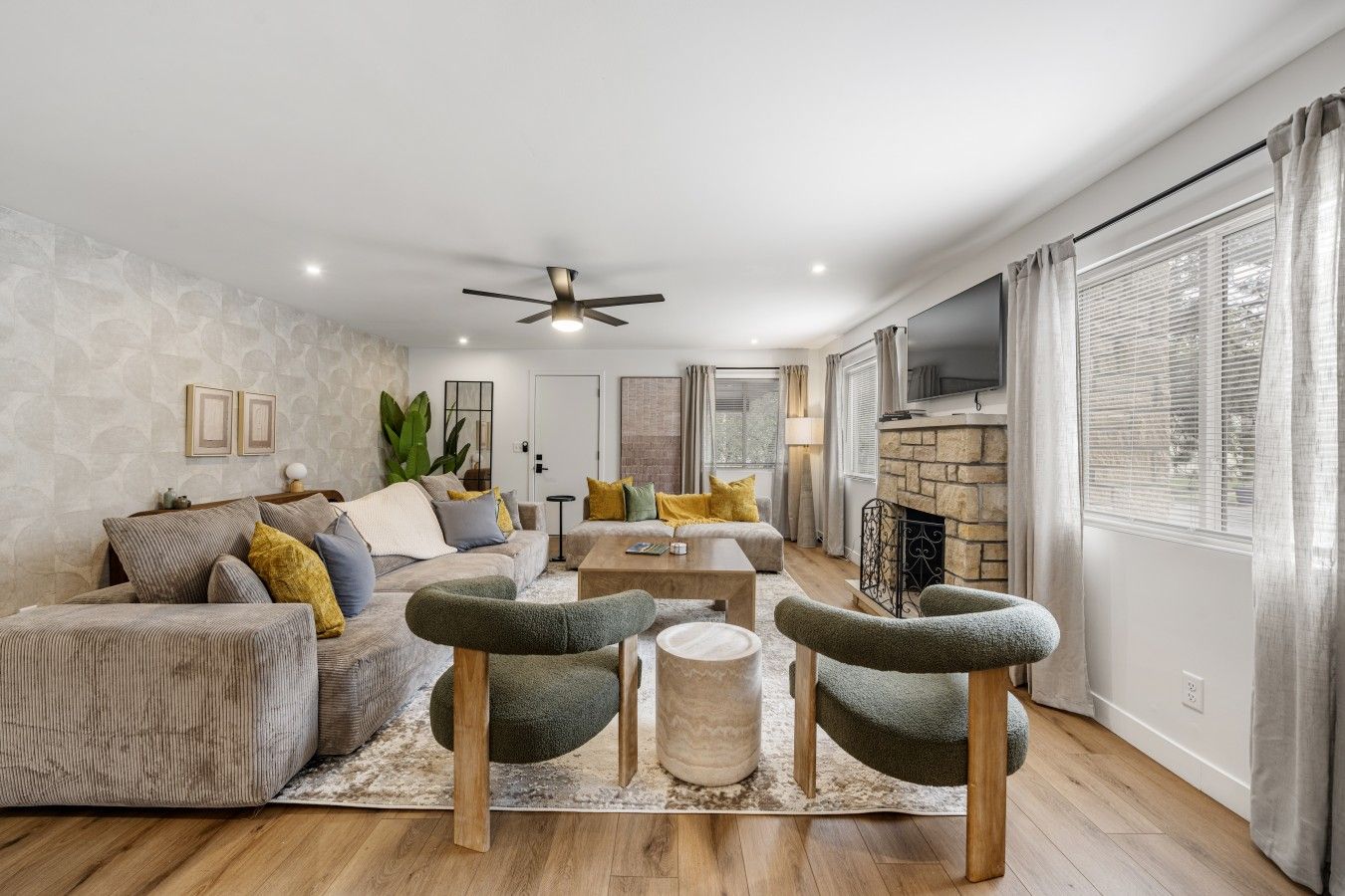 A modern living room with a sofa, armchairs, a coffee table, and a fireplace.