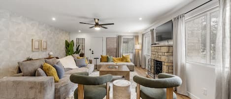 A modern living room with a sofa, armchairs, a coffee table, and a fireplace.