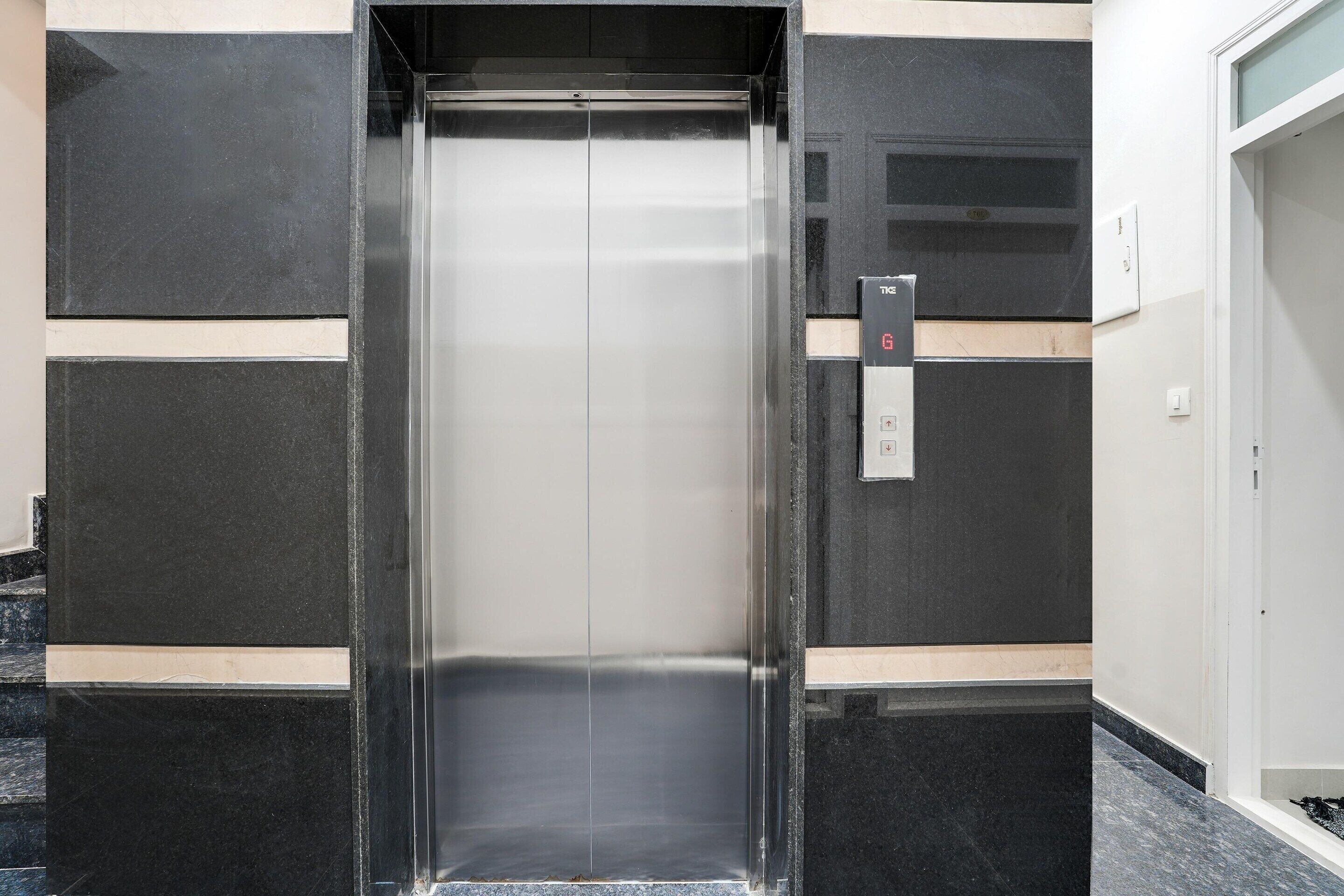 An elevator with a metallic interior and a control panel on the wall.