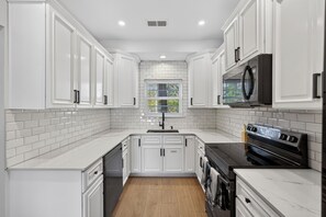 A modern kitchen with white cabinetry, a black oven, and a window with blinds. - Three Bedroom New Lakefront Retreat in Charleston (North Charleston)