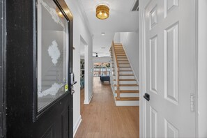 A hallway with a staircase, white walls, and a wooden floor. - Three Bedroom New Lakefront Retreat in Charleston (North Charleston)