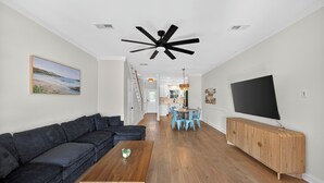 Een moderne woonkamer met een donkere bank, een houten salontafel en een televisie op een houten kast.