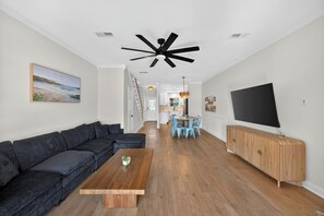 A modern living room with a dark sofa, wooden coffee table, and a TV on a wooden cabinet. - Three Bedroom New Lakefront Retreat in Charleston (North Charleston)