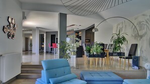 Ein modernes Wohnzimmer mit einem blauen Sofa, einem Glastisch und einer Treppe, die in einen anderen Bereich führt.