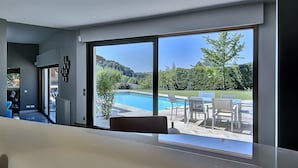 Ein modernes Interieur mit einer großen Schiebeglaswand, die zu einem Außenpoolbereich führt.