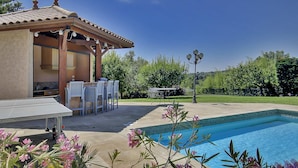 Ein Poolbereich mit Pergola, Sitzgelegenheiten im Freien und Blick auf die umliegende Landschaft.