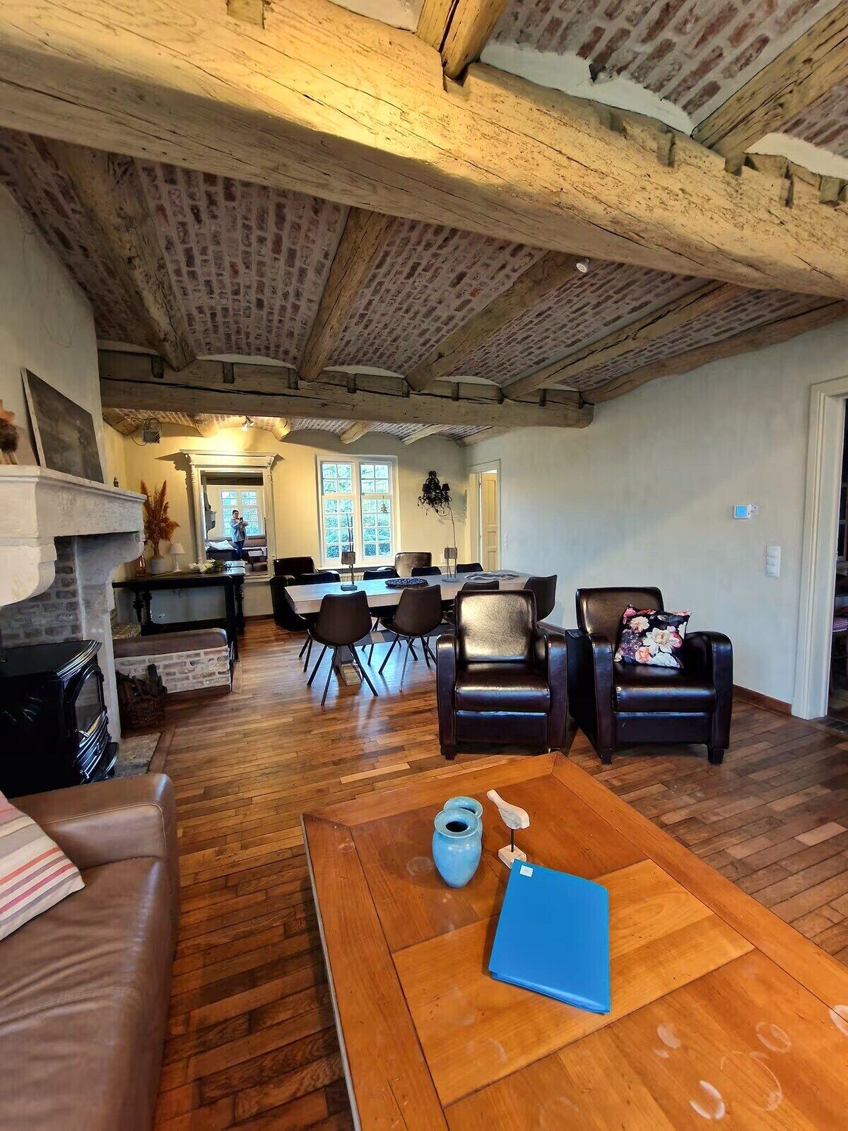 A spacious living room with a fireplace, a dining area, and a kitchen in the background.