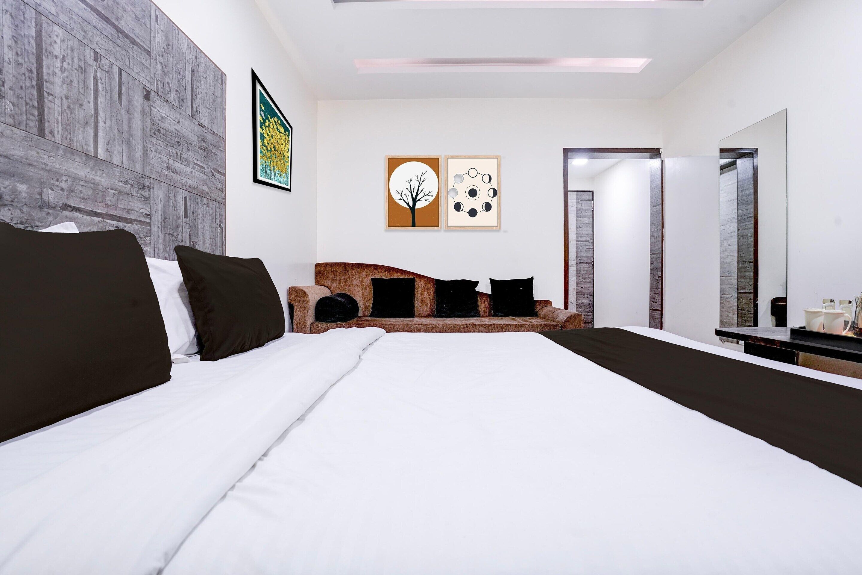 A modern bedroom with a large bed, a sofa, and a mirror.