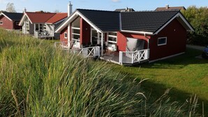A row of red houses with white railings, a grassy field, and a clear sky. - Baltic Coast Home With Private Spa (Grossenbrode)