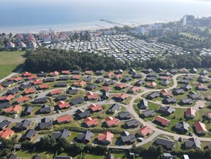 An aerial view of a residential area with houses arranged in a grid pattern, a bridge, and a body of water in the background. - Baltic Coast Home With Private Spa (Grossenbrode)