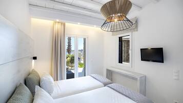Een hotelkamer met twee bedden, een televisie, een groot raam en een plafondventilator.
