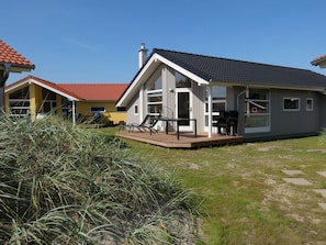 A modern house with a deck, a covered outdoor seating area, and a large window. - 4 Star Holiday Home in Grossenbrode (Grossenbrode)