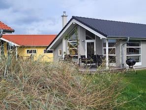 A modern house with a grey roof, a red-tiled roof, and a balcony with outdoor furniture. - 4 Star Holiday Home in Grossenbrode (Grossenbrode)