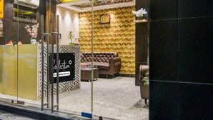 A reception area with a glass partition, a reception desk, a clock, and a patterned wall. - Classic With Twin Bed Hotel Paradise (Barasat)