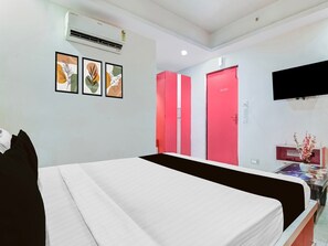 Une chambre d’hôtel avec un lit, une télévision, un bureau agrémenté d’un vase et des portes rouges.