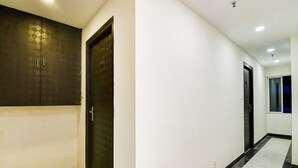 A hallway with a dark door, white walls, and a tiled floor. - Classic With Twin Bed Hotel Paradise (Barasat)