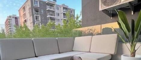 A balcony with a sofa, a wooden table, and two candles.