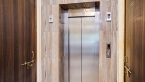 An elevator with a digital display, metallic interior, and wooden paneling on the walls. - Deluxe Royal Stay Inn (Prayagraj)