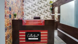A reception desk with a 'Collection' sign, patterned wallpaper, and a plant on the wall. - Deluxe Royal Stay Inn (Prayagraj)