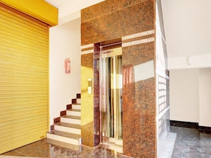 Una escalera con una puerta de cristal que da a una habitación, una puerta amarilla y un extintor en la pared.