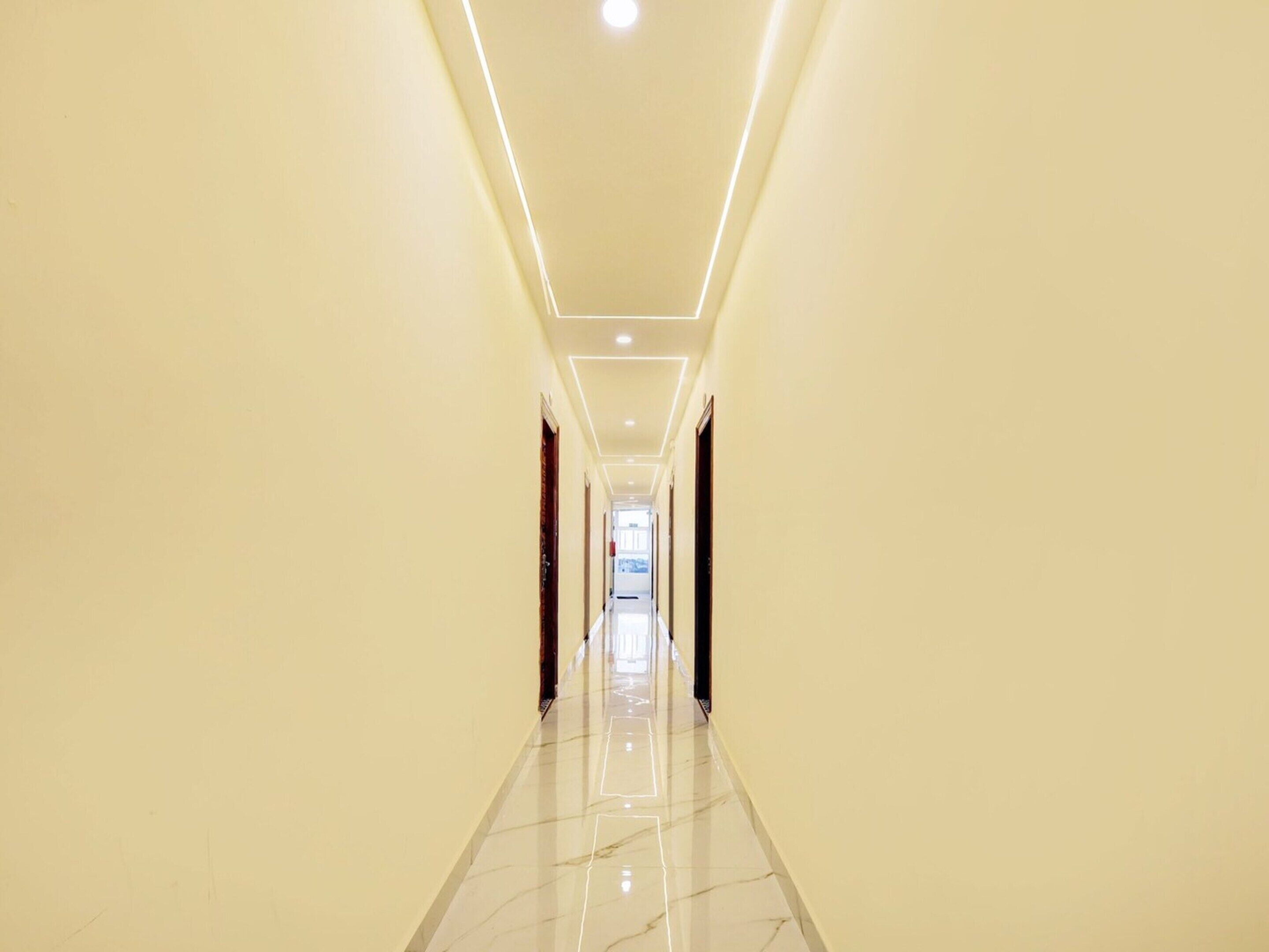 A long, narrow hallway with a glossy marble floor and recessed lighting.